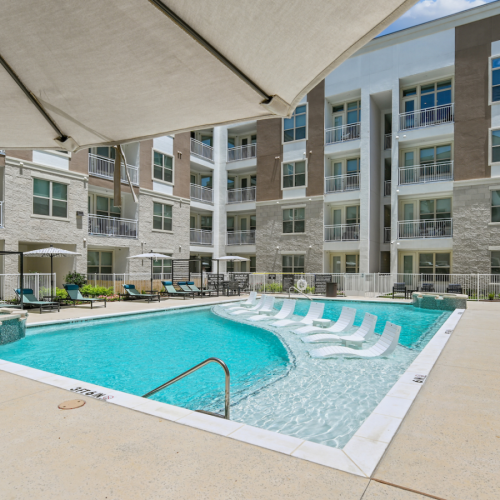 pool with lounge chairs and a large building in the back